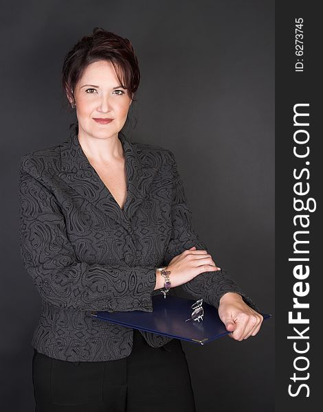 Composed Businesswoman holding a blue file against a black background. Composed Businesswoman holding a blue file against a black background