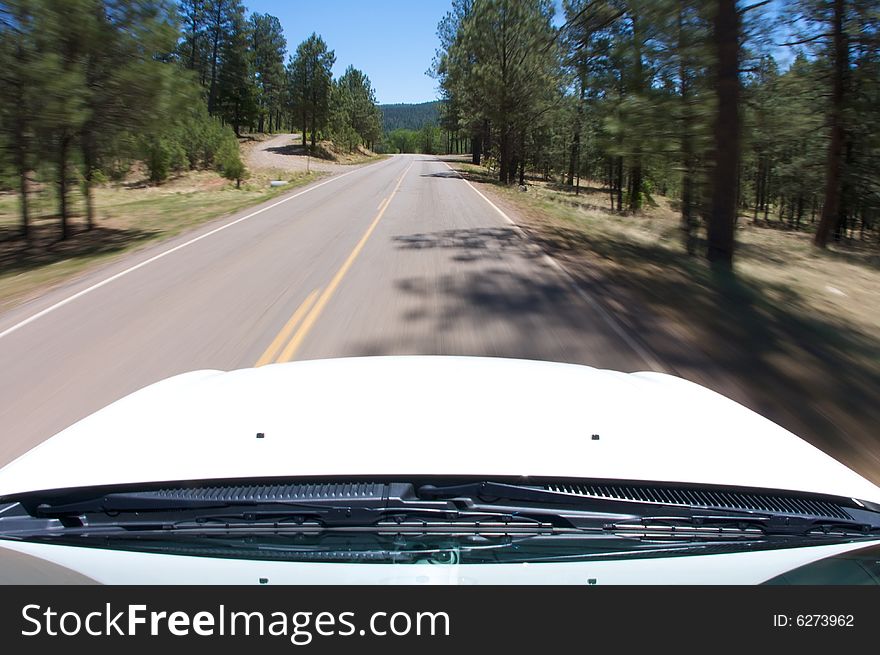 An image a view of a mountain road from inside a car. An image a view of a mountain road from inside a car