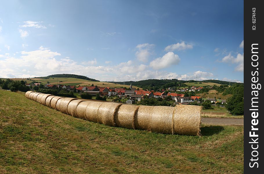 Haybales in a german landscape in the north of Hesse. In the background the village of Mühlbach (Neuenstein) in the Knüll mountains.Hay bales on an idyllic field near Kassel and Ahnatal-Weimar in Germany