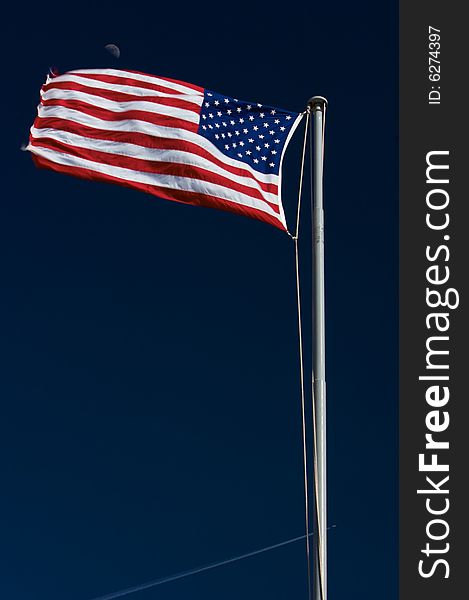 An image of an American flag waving with the moon in the background. An image of an American flag waving with the moon in the background