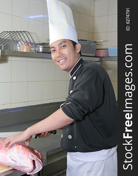 Chef butchering red snapper fish smiling. Chef butchering red snapper fish smiling