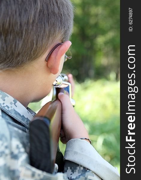 Young child in us army style cammo holding play rifle and aiming it into the woods; child in focus; background intentionally blurred. Young child in us army style cammo holding play rifle and aiming it into the woods; child in focus; background intentionally blurred