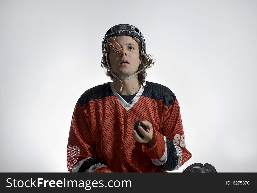 A young hockey player sitting.  He is playfully juggling two hockey pucks. Horizontally framed shot. A young hockey player sitting.  He is playfully juggling two hockey pucks. Horizontally framed shot.