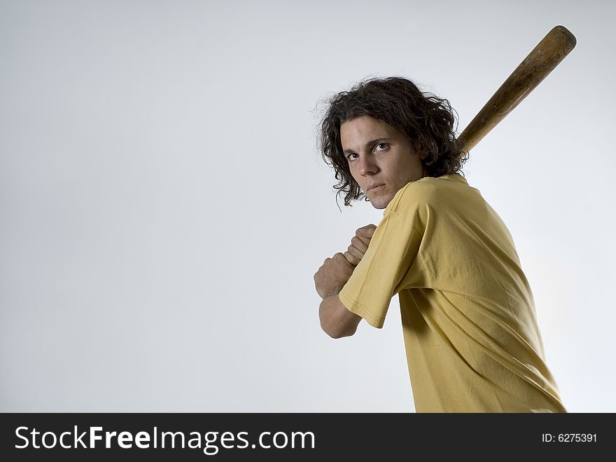 An young man holding a bat.  He is looking at the camera, and has a serious expression on his face.  Horizontally framed shot. An young man holding a bat.  He is looking at the camera, and has a serious expression on his face.  Horizontally framed shot.