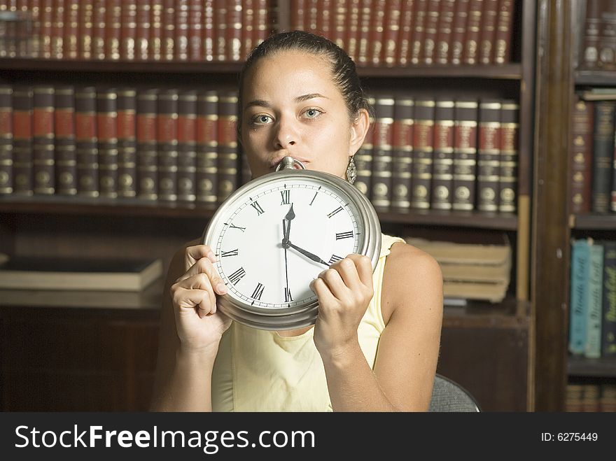 Woman in office holding clock in front of face. Horizontally framed photo. Woman in office holding clock in front of face. Horizontally framed photo.