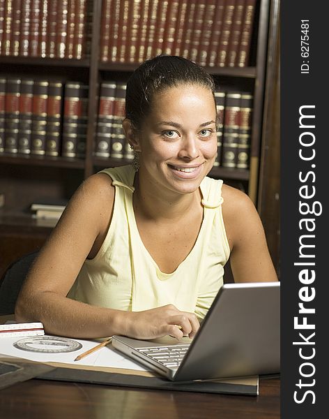 Smiling woman sitting at desk with laptop computer. Vertically framed photo. Smiling woman sitting at desk with laptop computer. Vertically framed photo.