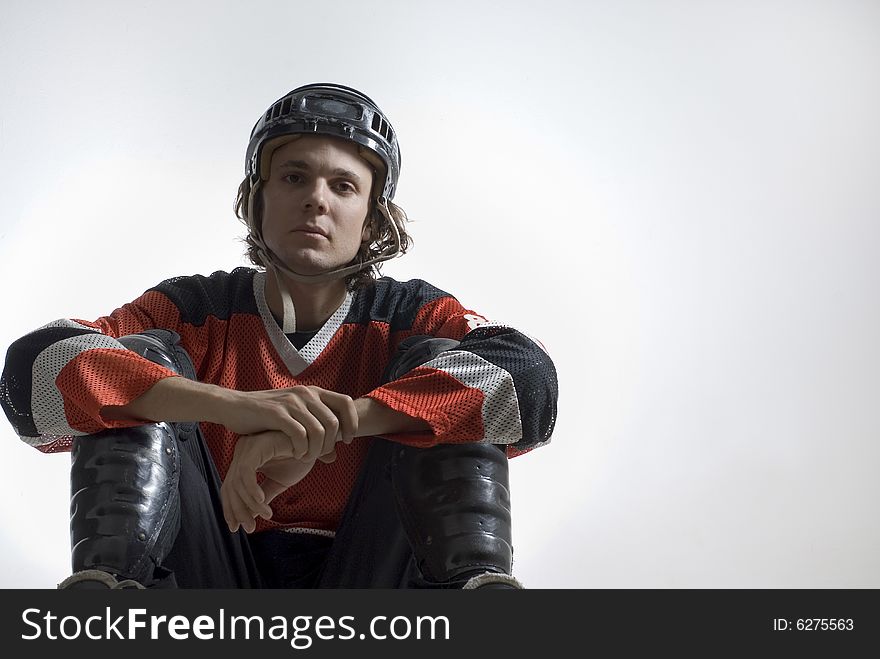 A young hockey player sitting.  He is facing the camera and has a passive expression on his face. Horizontally framed shot. A young hockey player sitting.  He is facing the camera and has a passive expression on his face. Horizontally framed shot.