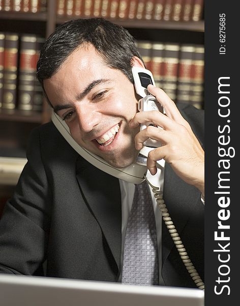 Happy businessman on phone in office. Vertically framed photo.