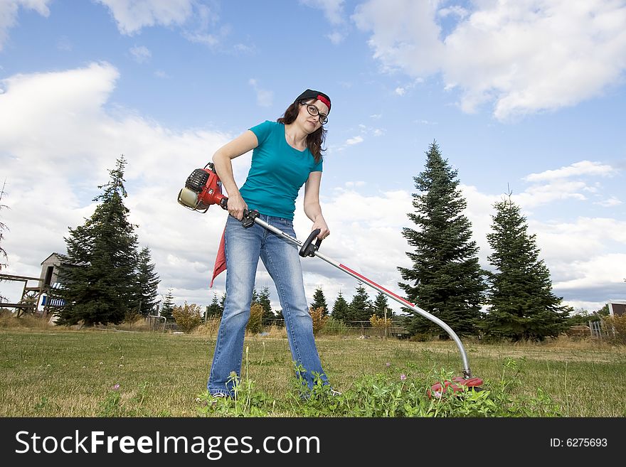 Unhappy woman in a field using a weedwacker. Horizontally framed photo. Unhappy woman in a field using a weedwacker. Horizontally framed photo.