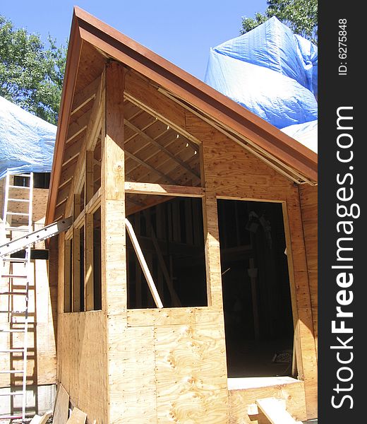 Part of timber construction showing ridge pole, rafters, sheathing, roof line, openings for windows and blue tarpaulins. Part of timber construction showing ridge pole, rafters, sheathing, roof line, openings for windows and blue tarpaulins