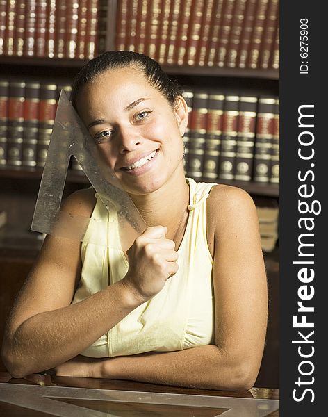 Smiling girl holding a drafting tool in an office full of books. Vertically framed photo. Smiling girl holding a drafting tool in an office full of books. Vertically framed photo.