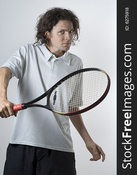 An athlete holding a tennis racket.  He is looking at the camera.  He has a serious expression on his face. Vertically framed shot. An athlete holding a tennis racket.  He is looking at the camera.  He has a serious expression on his face. Vertically framed shot.