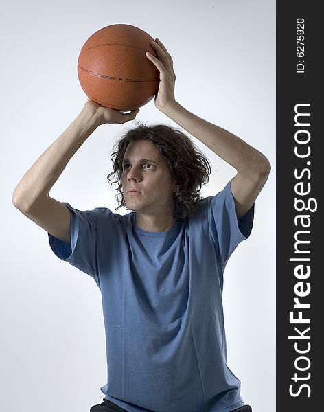 A young man holding a basketball.  He is focusing on shooting the ball. Vertically framed shot. A young man holding a basketball.  He is focusing on shooting the ball. Vertically framed shot.
