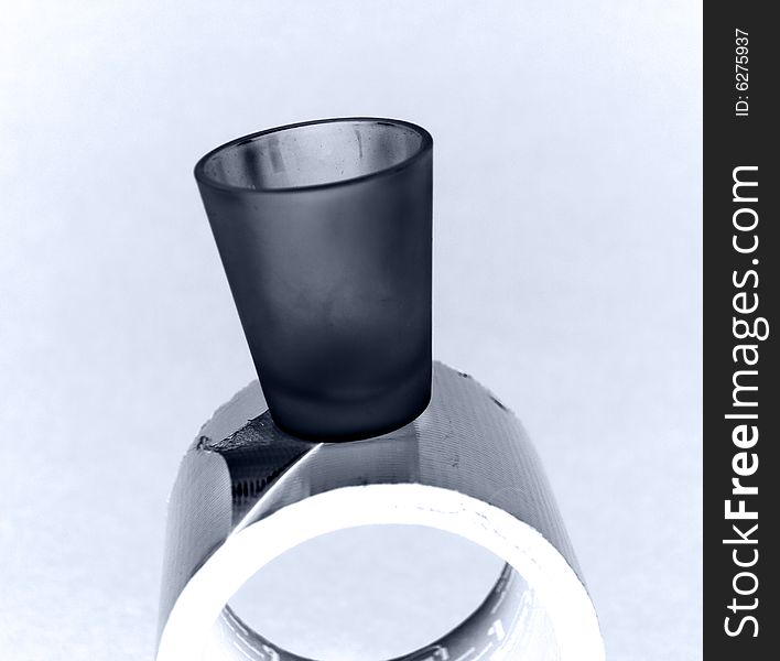 A shot glass precariously placed on a roll of duct tape. A shot glass precariously placed on a roll of duct tape