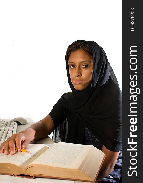 A young Muslim woman wearing a black head scarf looking at the camera. Studying with a computer and a book. A young Muslim woman wearing a black head scarf looking at the camera. Studying with a computer and a book.