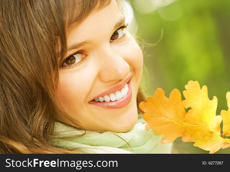 Beautiful romantic brunette with golden autumn leaf close-up portrait