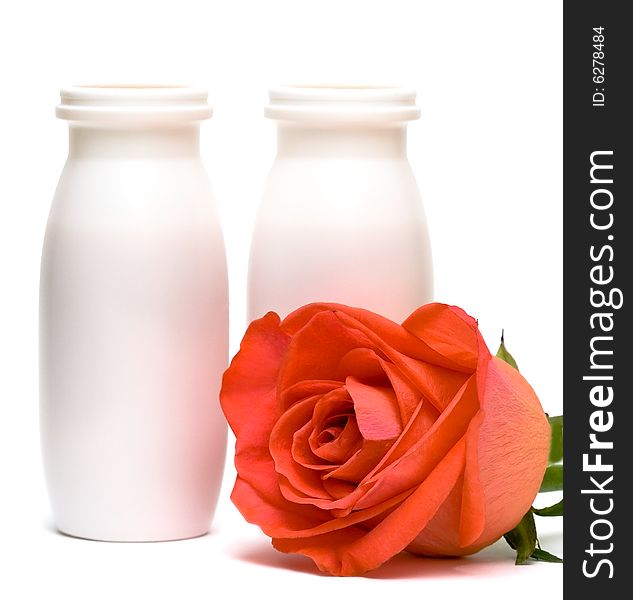 Jars with milk and rose over white background