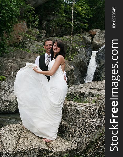 Happy bride and groom standing on top of a mountain.