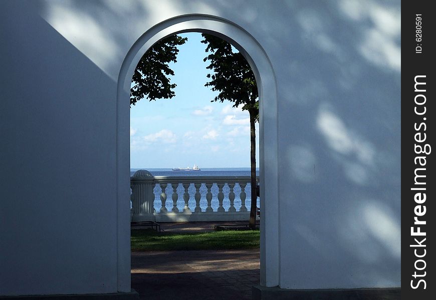 Arch in a white wall with a kind at the seaside