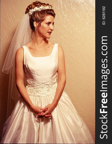 Woman dressed in bridal gown. looking right, hands folded at wedding. Woman dressed in bridal gown. looking right, hands folded at wedding.