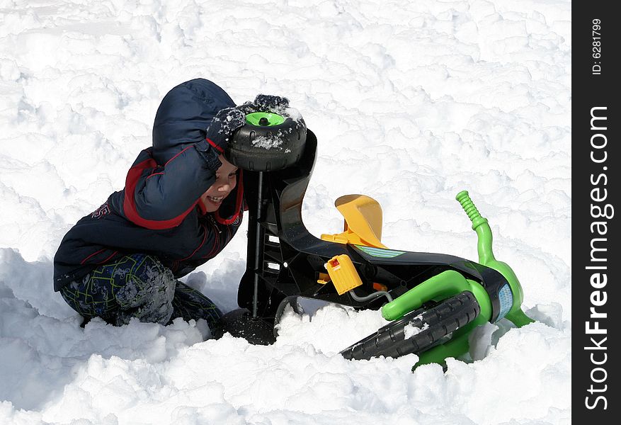 Young boy playing with a three wheeled toy in the snow. Young boy playing with a three wheeled toy in the snow