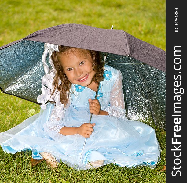 Portrait of little girl in blue dress on the green grass under umbrella. Portrait of little girl in blue dress on the green grass under umbrella