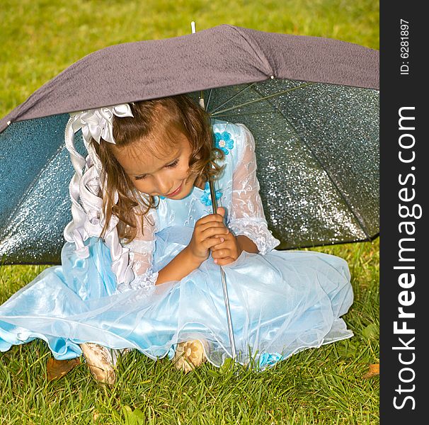 Closeup portrait of little girl sitting under umbrella on green grass. Closeup portrait of little girl sitting under umbrella on green grass