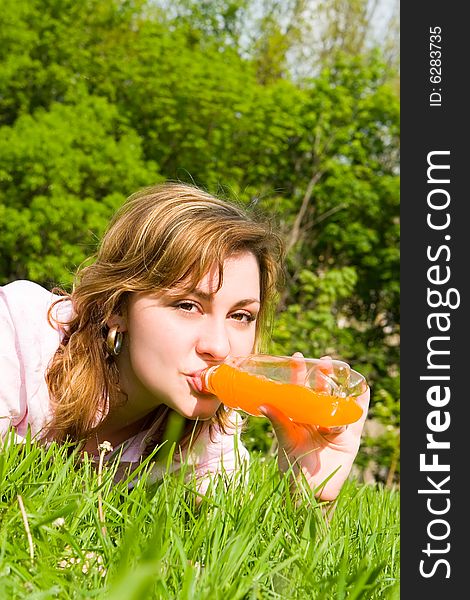 Pretty woman drinking juice on the summer glade