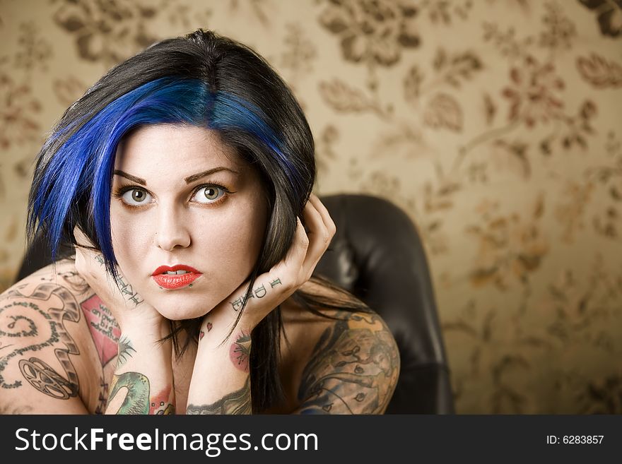 Pretty young woman with many tattoos in a leather chair. Pretty young woman with many tattoos in a leather chair
