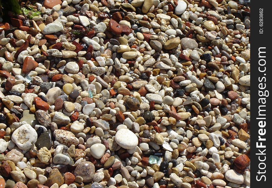 The multi-coloured stones laying on seacoast.