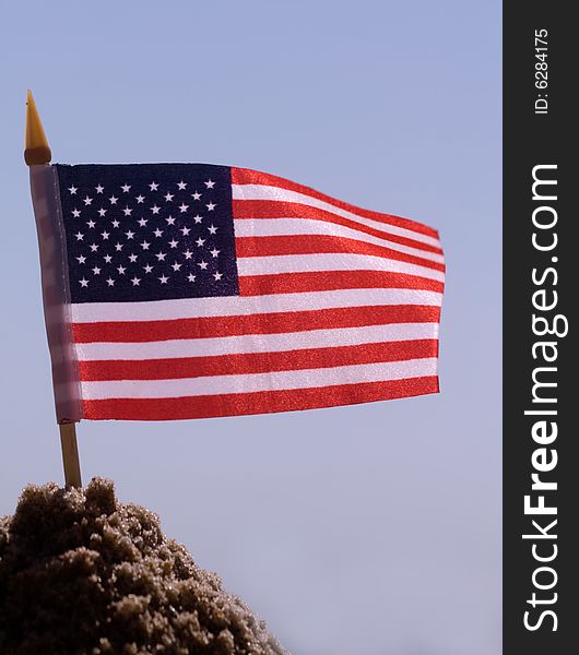 A united states of america flag in the sand on a sunny day. A united states of america flag in the sand on a sunny day.