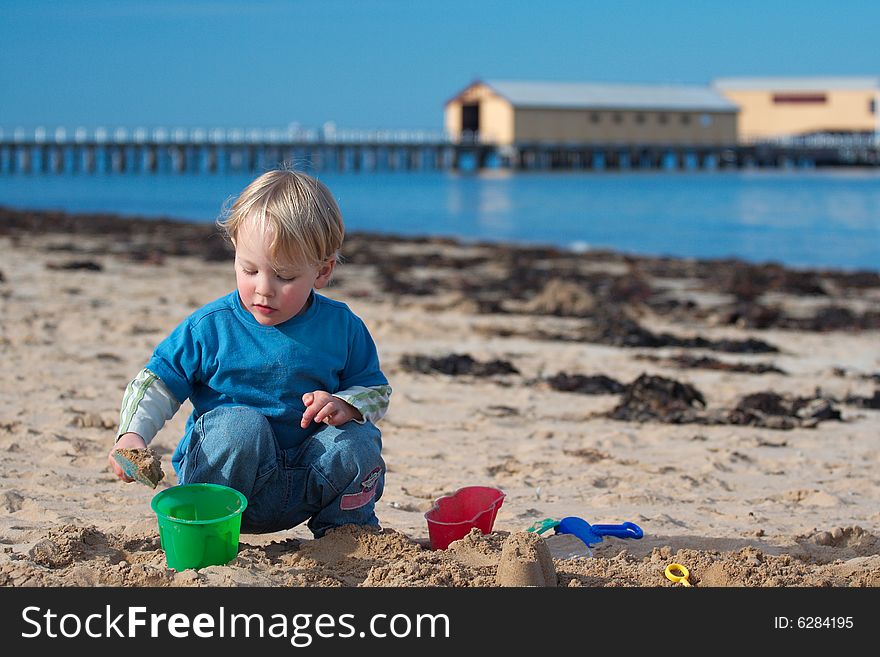 A young boy building sand castles on the beach. A young boy building sand castles on the beach.