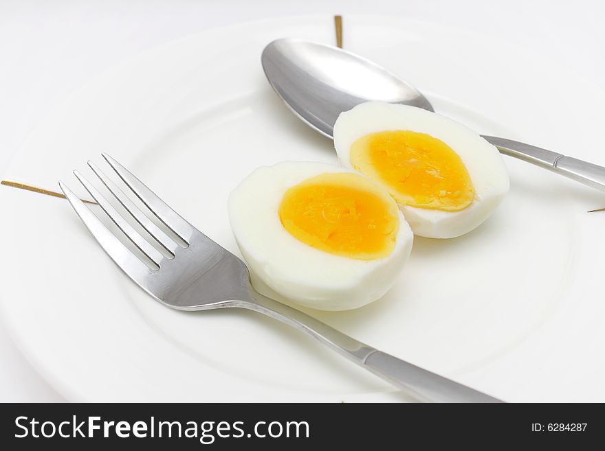 Cooked egg put on white plate with folk and spoon. Cooked egg put on white plate with folk and spoon.