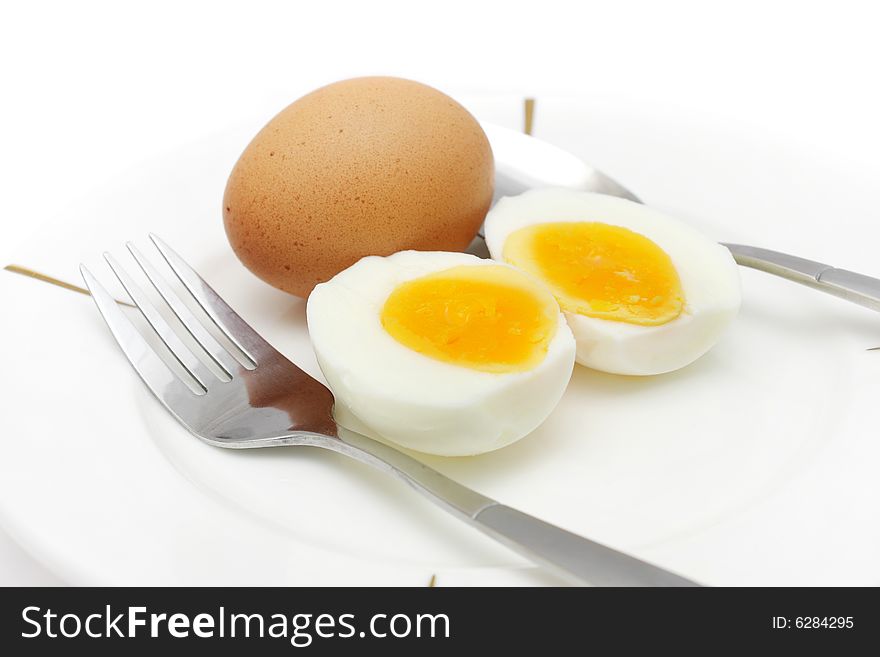 Cooked egg put on white plate with folk and spoon. Cooked egg put on white plate with folk and spoon.