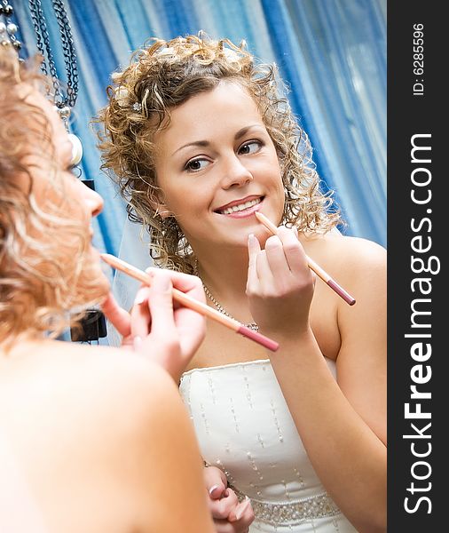 Pretty smiling bride paints her lips near the mirror. Pretty smiling bride paints her lips near the mirror