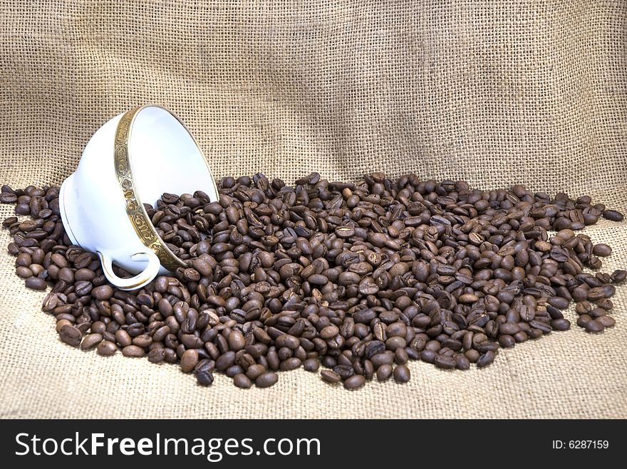 Coffee beans with a coffee cup, sack as background
