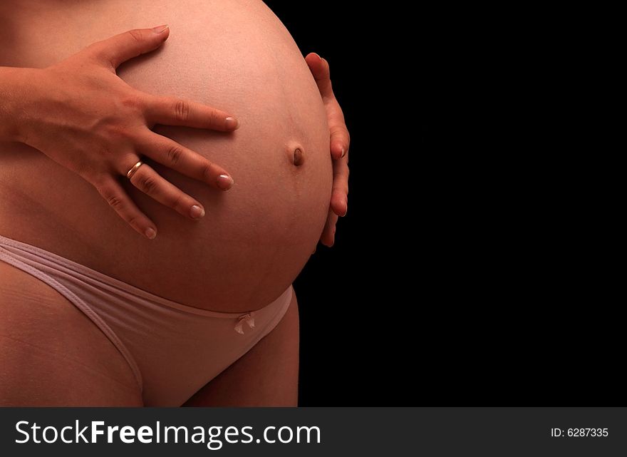 Pregnant woman holding stomach, side view. Pregnant woman holding stomach, side view