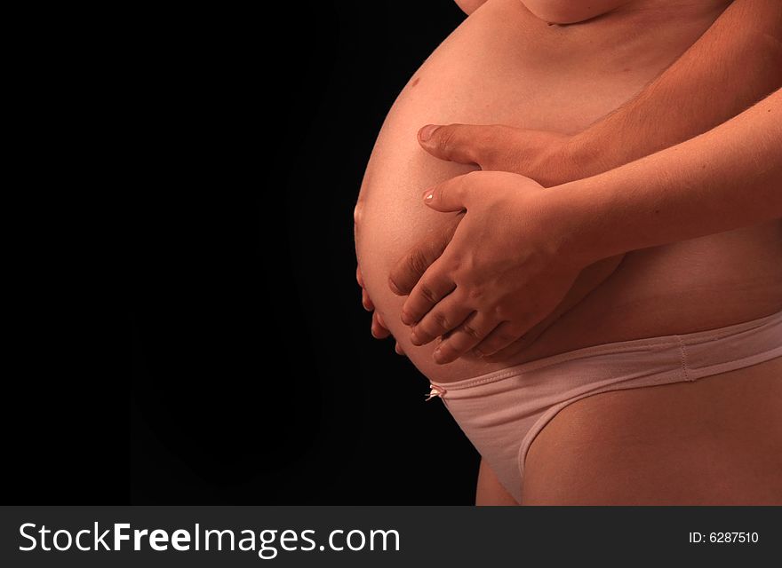 Hands hold a pregnant belly, side view. Hands hold a pregnant belly, side view
