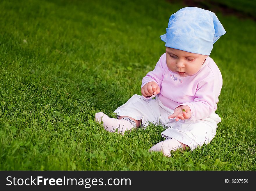 Little baby sitting comfort in park on green grass.