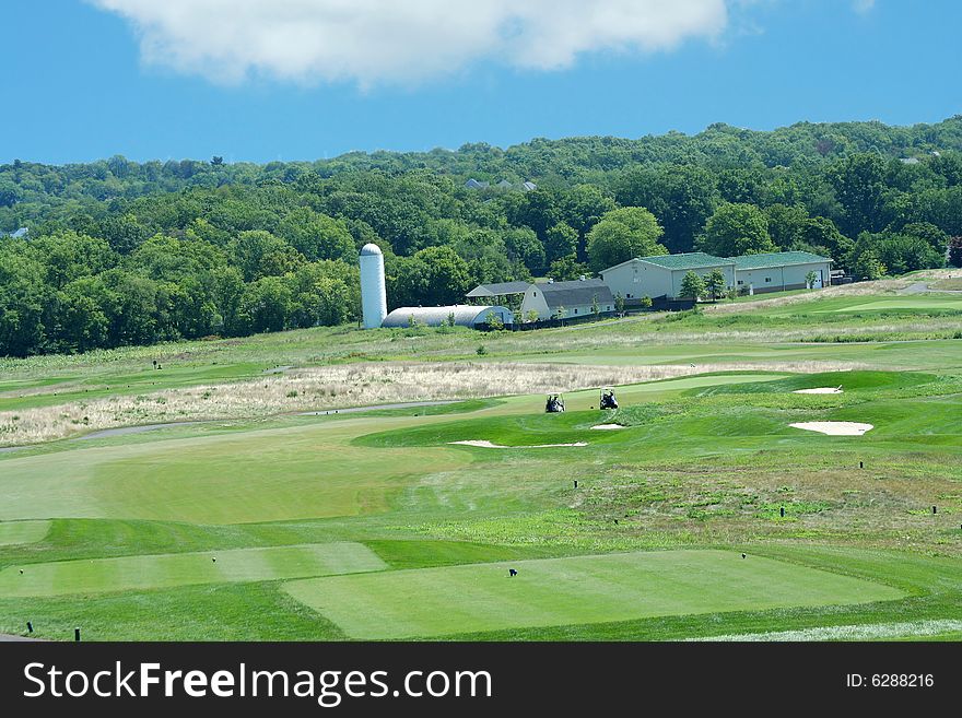 A Golf course with farm in the background