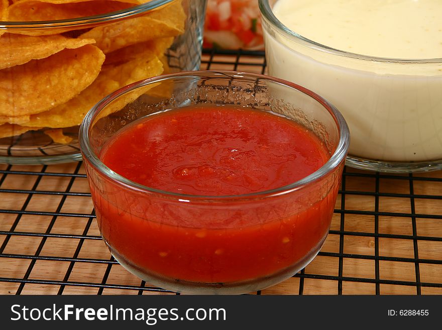 Glass bowls of salsa, cheese dip and tortilla chips in kitchen or restaurant. Glass bowls of salsa, cheese dip and tortilla chips in kitchen or restaurant.