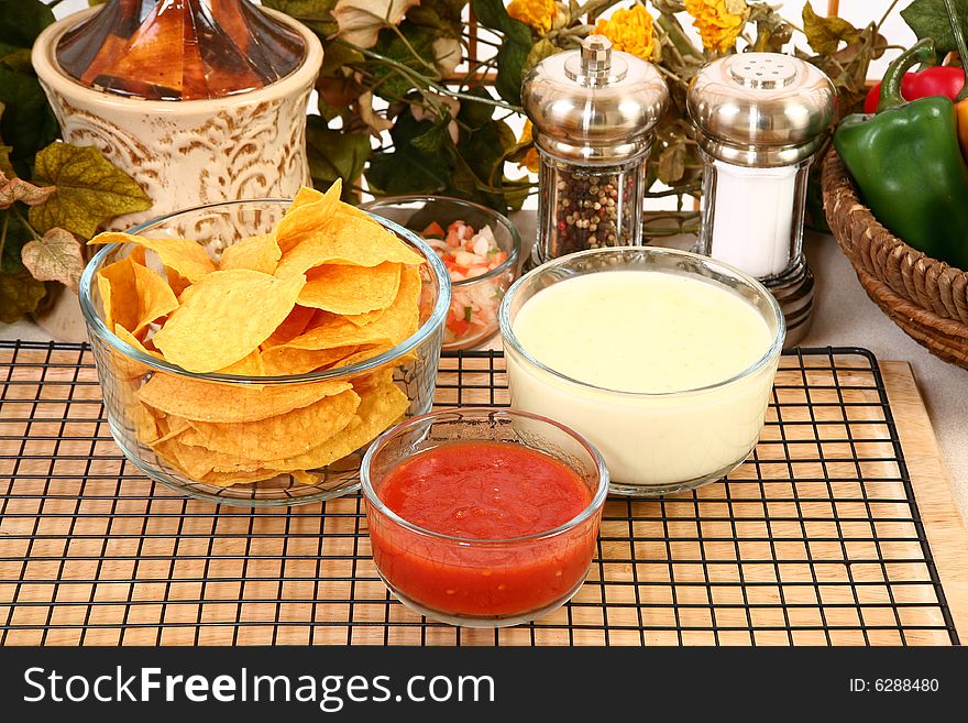 Glass bowls of salsa, cheese dip and tortilla chips in kitchen or restaurant. Glass bowls of salsa, cheese dip and tortilla chips in kitchen or restaurant.