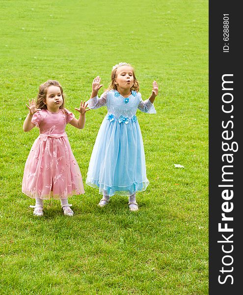 Two little girls are playing on green grass. Two little girls are playing on green grass