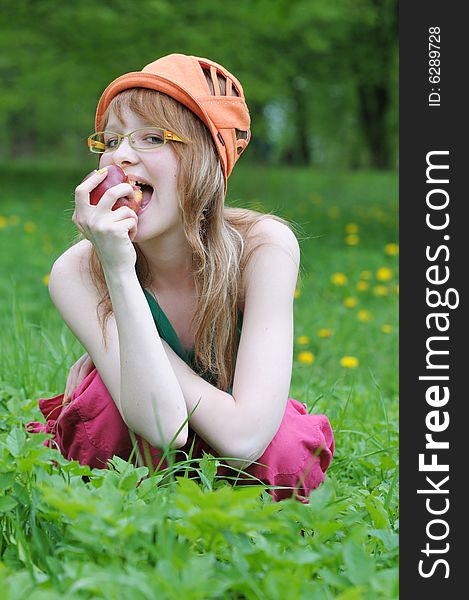 Happy young girl spectacled eats an apple. Happy young girl spectacled eats an apple