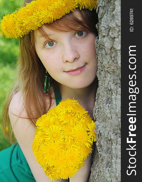 Girl with red hair and diadem from yellow dandelions on head