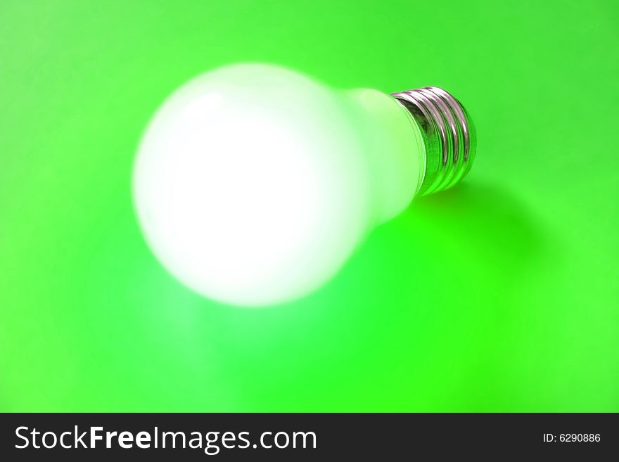 Illuminated lightbulb on green background