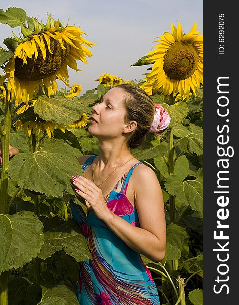Young woman between two big sunflowers at sunny day