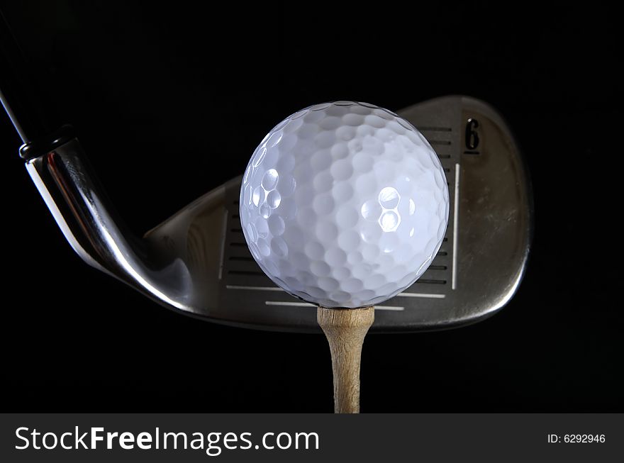 Golf club with ball on a tee in the black background. Golf club with ball on a tee in the black background