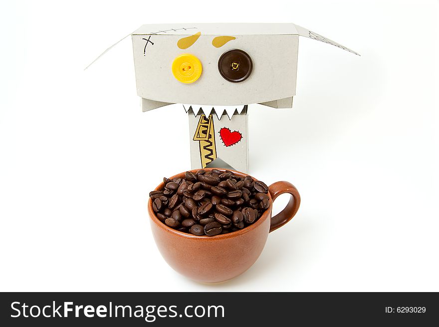 Cup with coffee beans and cardboard toy with insane expression. Cup with coffee beans and cardboard toy with insane expression