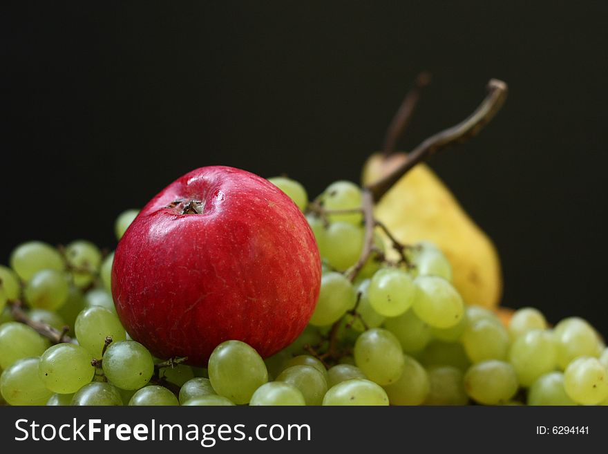Red apple, green grape and yellow pear on black background. Red apple, green grape and yellow pear on black background
